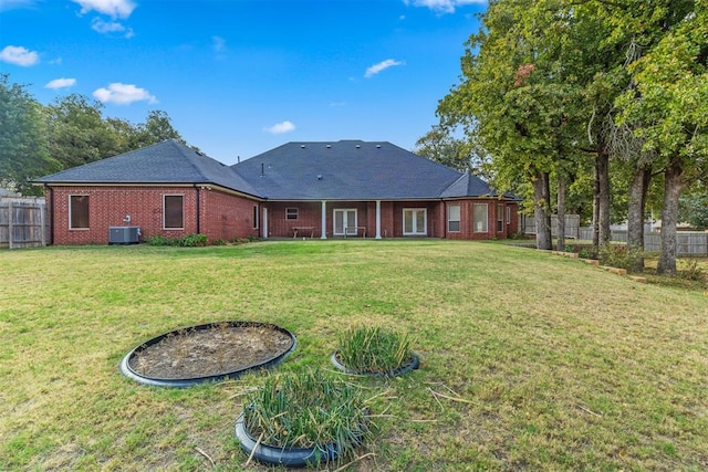 back of house featuring central AC unit and a yard