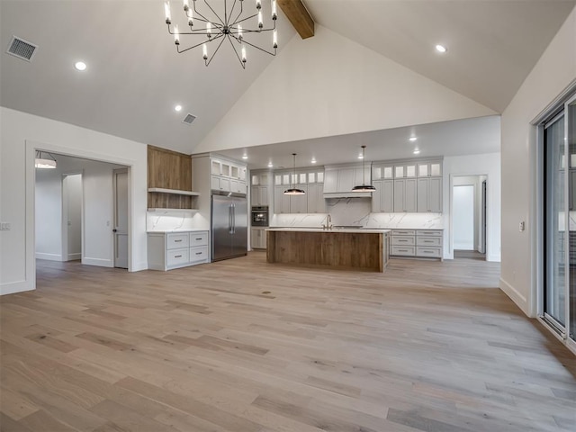 kitchen featuring pendant lighting, high vaulted ceiling, a spacious island, light wood-type flooring, and appliances with stainless steel finishes