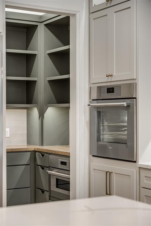 kitchen featuring stainless steel oven and white cabinetry