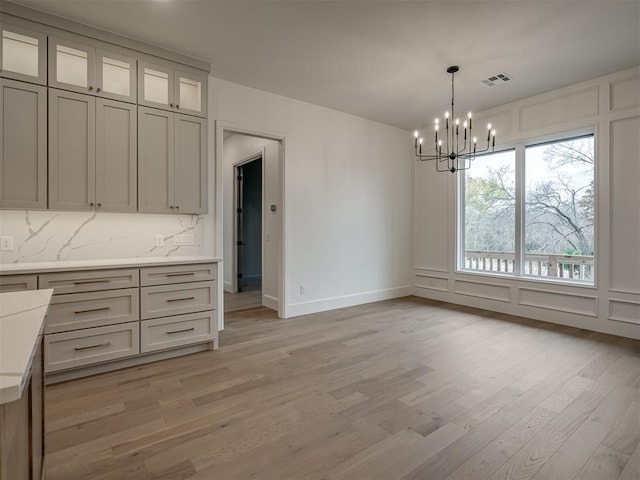 unfurnished dining area with a chandelier and light wood-type flooring