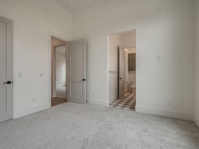 unfurnished bedroom with light colored carpet and connected bathroom