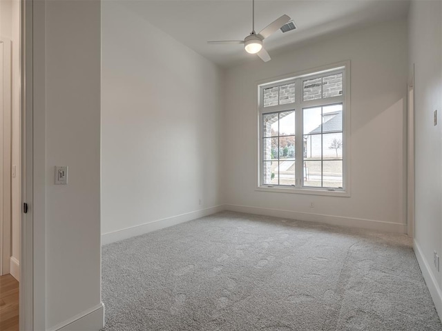 empty room featuring ceiling fan and light carpet