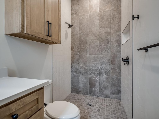 bathroom with vanity, toilet, and tiled shower