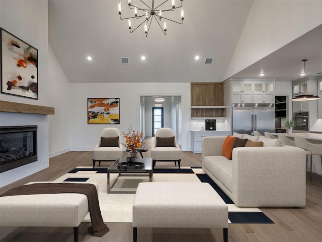 living room featuring an inviting chandelier, high vaulted ceiling, and light wood-type flooring