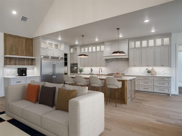 living room with sink, high vaulted ceiling, and light hardwood / wood-style flooring