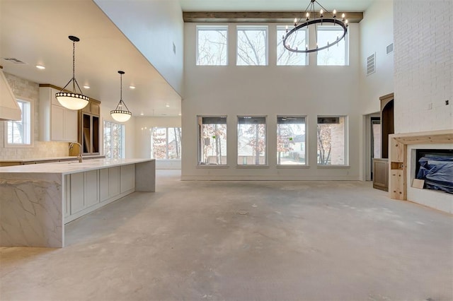 unfurnished living room featuring an inviting chandelier, sink, and a fireplace