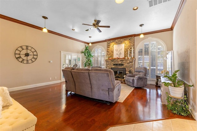 living room featuring crown molding, hardwood / wood-style floors, ceiling fan, and a brick fireplace