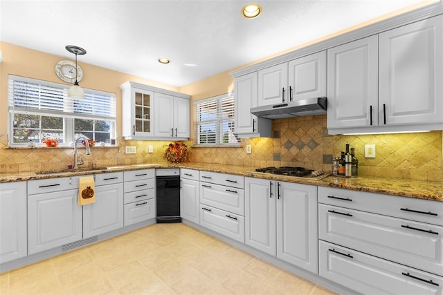 kitchen with tasteful backsplash, light stone counters, sink, white cabinets, and hanging light fixtures