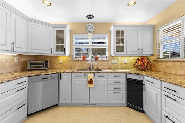 kitchen with stainless steel dishwasher, plenty of natural light, white cabinets, and sink