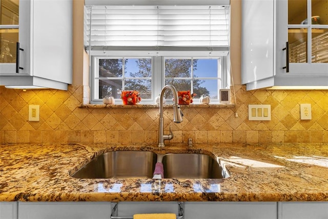 kitchen with backsplash, white cabinetry, and sink