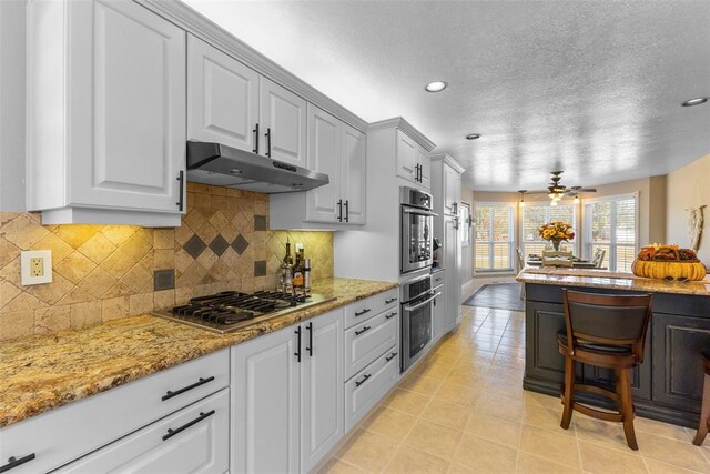 kitchen with ceiling fan, white cabinetry, backsplash, and stainless steel gas cooktop