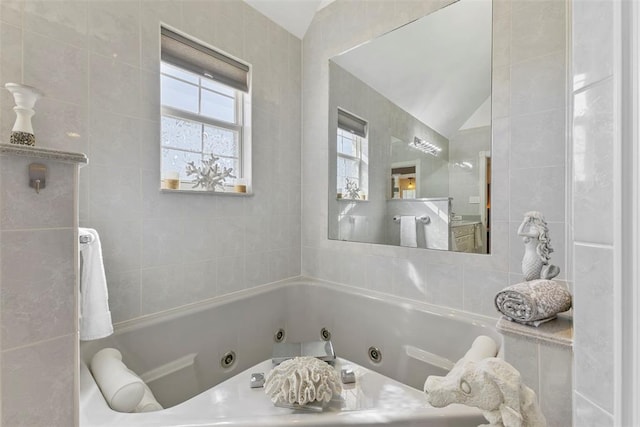 bathroom with lofted ceiling, a bath, and tile walls