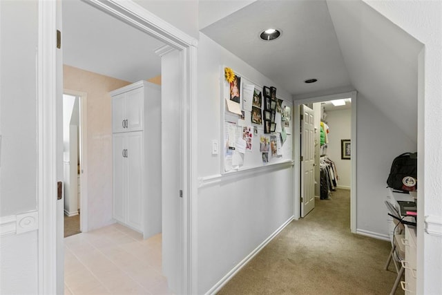 hallway featuring light carpet and vaulted ceiling