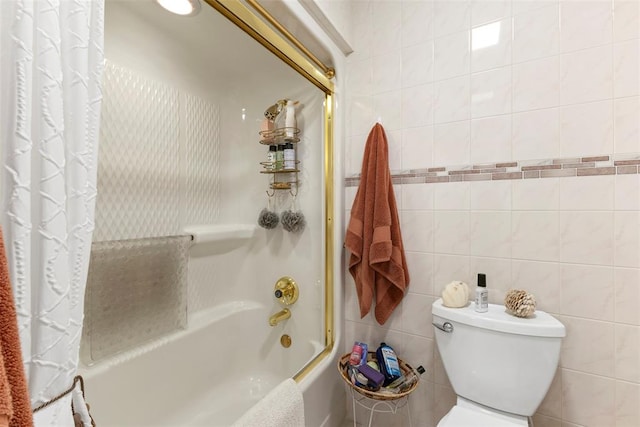 bathroom featuring tile walls, shower / bath combo, and toilet