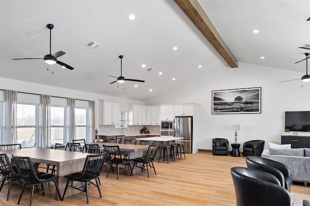 dining space featuring beamed ceiling, light wood-type flooring, sink, and high vaulted ceiling