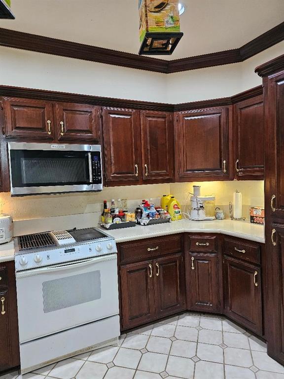 kitchen featuring dark brown cabinetry, white range oven, and crown molding