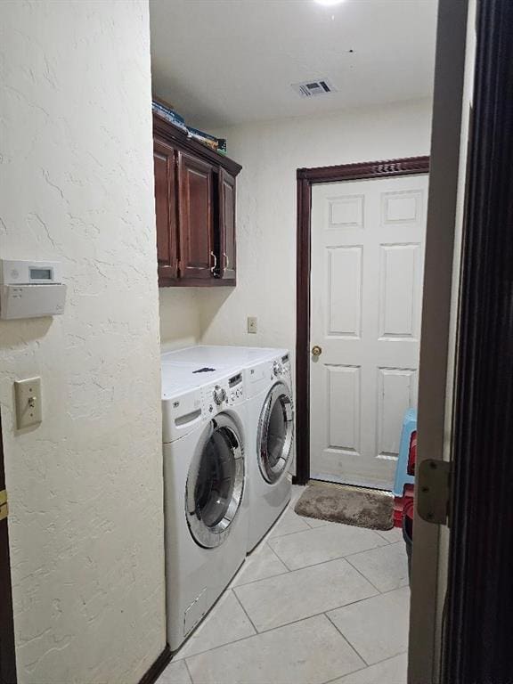 laundry area featuring washer and dryer, cabinets, and light tile patterned flooring