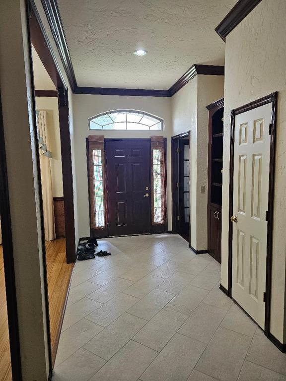 entrance foyer featuring light hardwood / wood-style floors, ornamental molding, and a textured ceiling