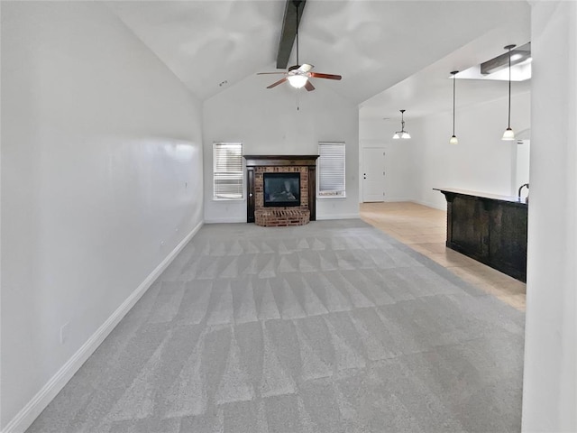 unfurnished living room featuring vaulted ceiling with beams, ceiling fan, light colored carpet, and a brick fireplace