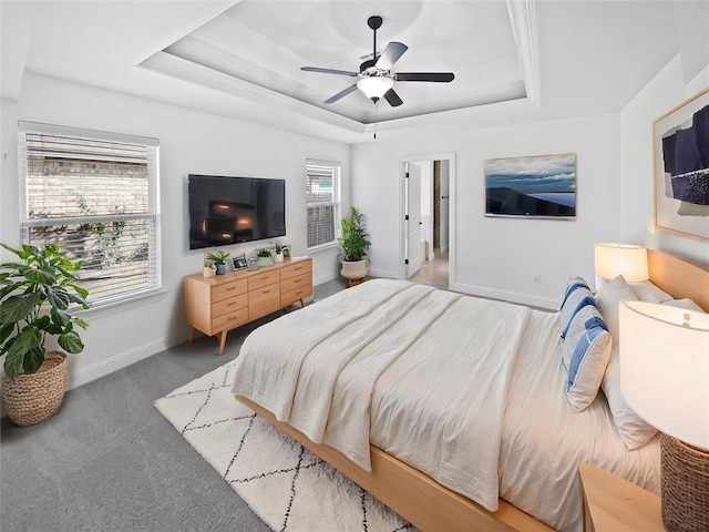 carpeted bedroom with a raised ceiling and ceiling fan