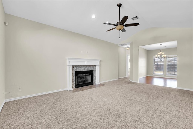 unfurnished living room featuring ceiling fan with notable chandelier, light colored carpet, lofted ceiling, and a tile fireplace