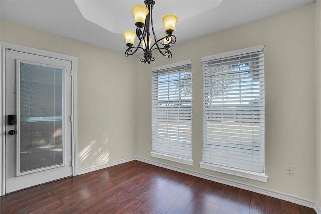 empty room with dark wood-type flooring and an inviting chandelier