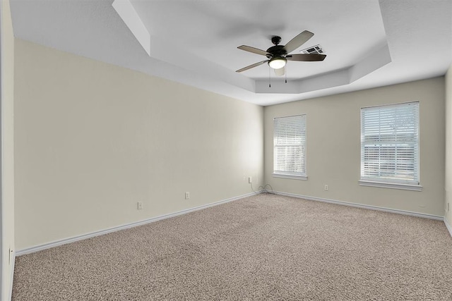 spare room featuring carpet floors, a raised ceiling, and ceiling fan