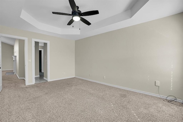 carpeted empty room featuring a raised ceiling and ceiling fan