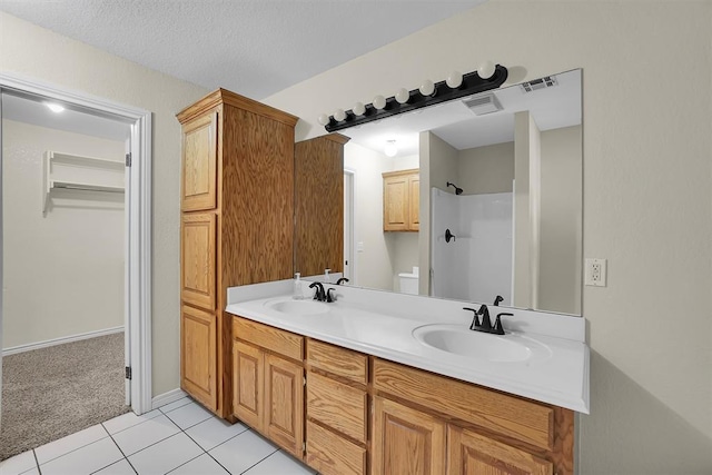 bathroom featuring tile patterned flooring, a shower, a textured ceiling, toilet, and vanity