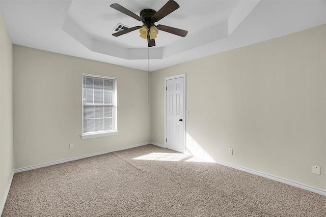 carpeted empty room with ceiling fan and a raised ceiling