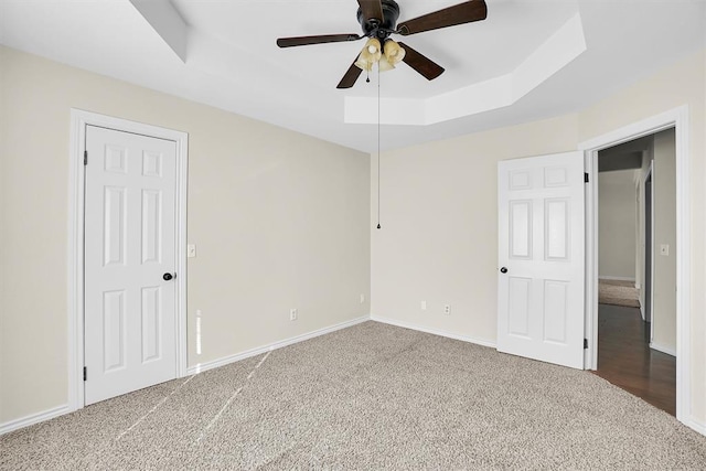516 S Quail Run, Altus, OK 73521 - unfurnished bedroom featuring a tray ceiling, carpet flooring, and ceiling fan
