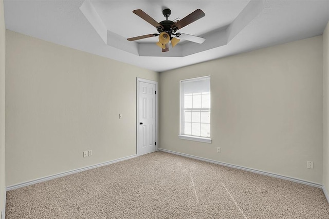 spare room featuring carpet flooring, ceiling fan, and a raised ceiling