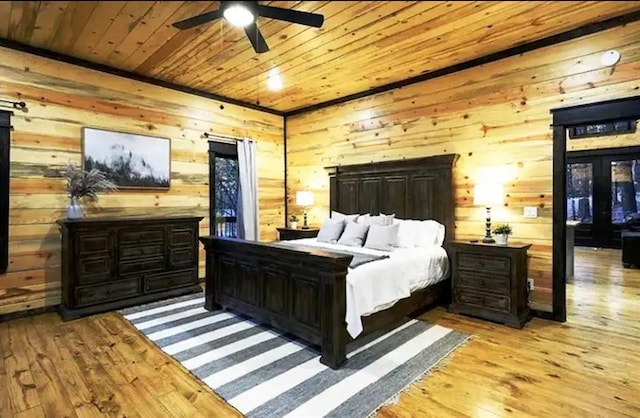 bedroom featuring ceiling fan, wood ceiling, wooden walls, and light hardwood / wood-style flooring