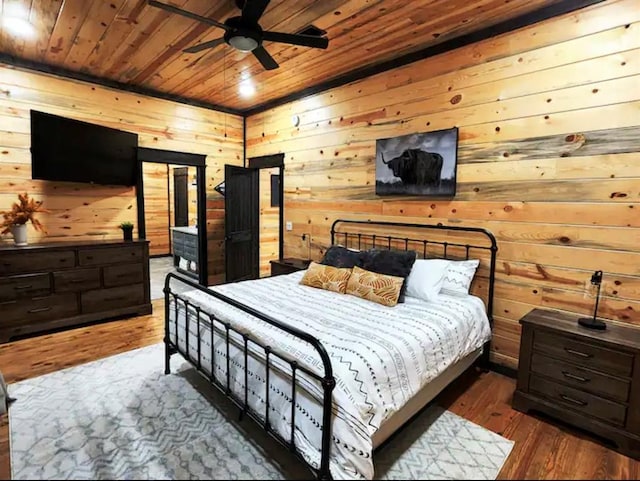 bedroom with ceiling fan, wooden ceiling, dark wood-type flooring, and wooden walls