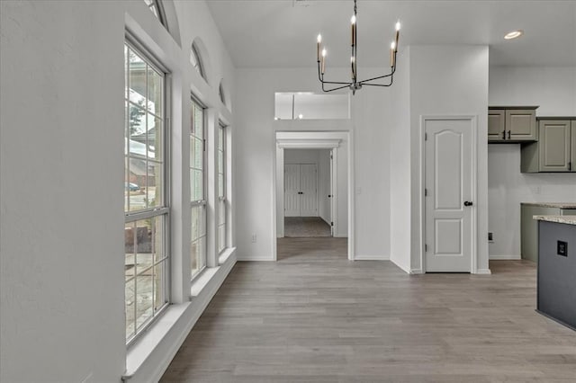 corridor with a chandelier and light wood-type flooring