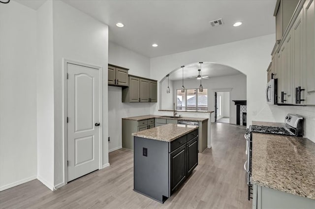 kitchen featuring ceiling fan, gray cabinetry, a kitchen island, pendant lighting, and stainless steel appliances