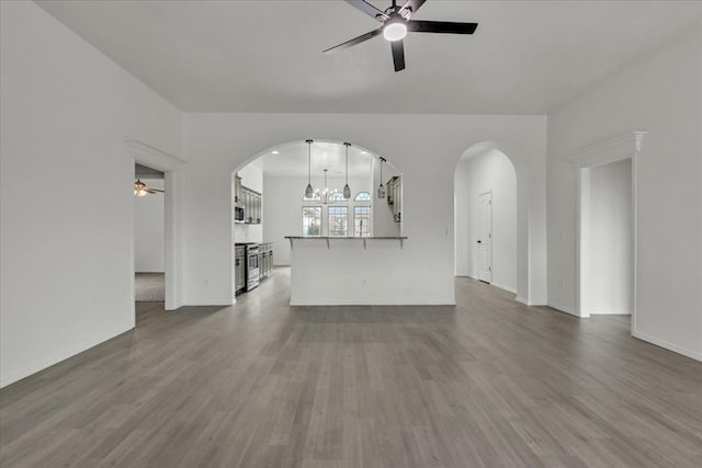 unfurnished living room featuring ceiling fan with notable chandelier and dark hardwood / wood-style flooring