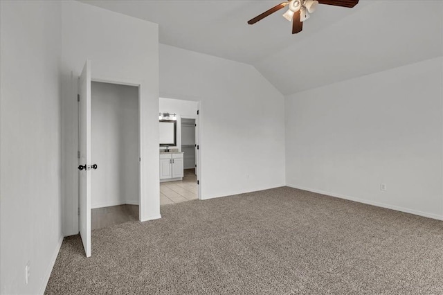 unfurnished bedroom with light carpet, connected bathroom, vaulted ceiling, and ceiling fan