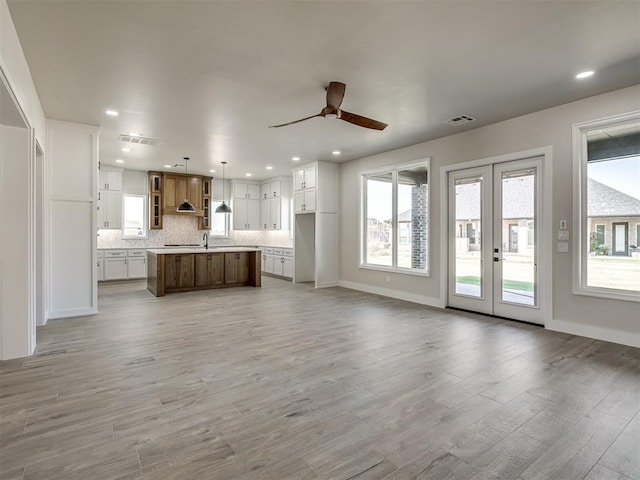 unfurnished living room with ceiling fan, french doors, and light hardwood / wood-style flooring