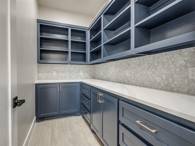 kitchen featuring tasteful backsplash, light stone countertops, and light wood-type flooring