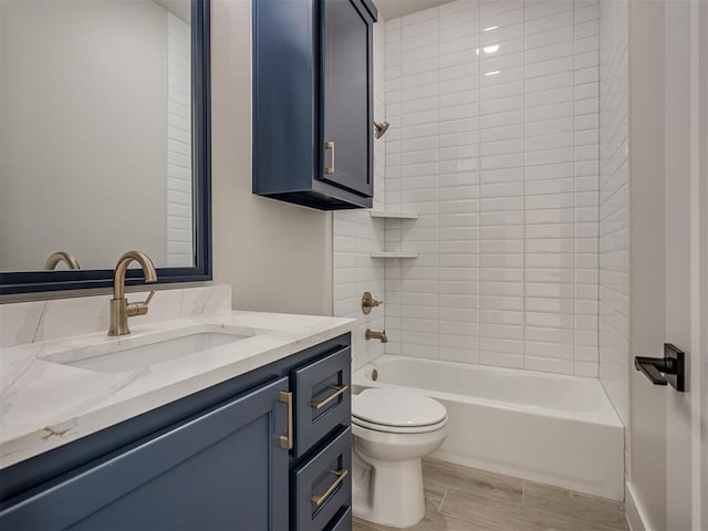 full bathroom with vanity, tiled shower / bath combo, hardwood / wood-style flooring, and toilet