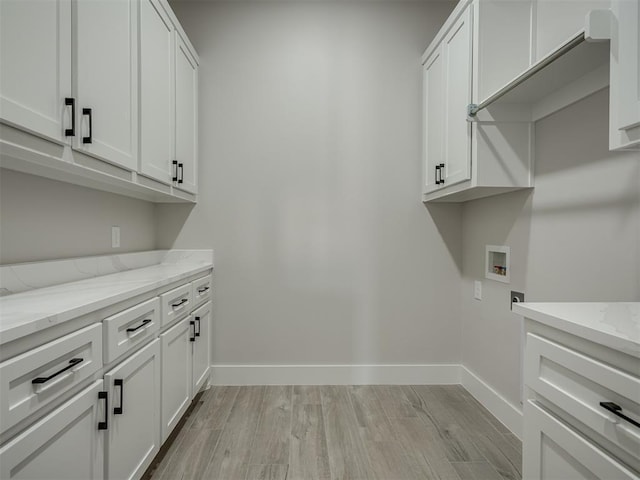 laundry room with washer hookup, cabinets, and light wood-type flooring