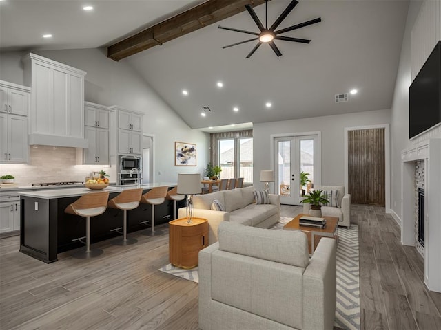 living room featuring high vaulted ceiling, sink, beam ceiling, light wood-type flooring, and french doors