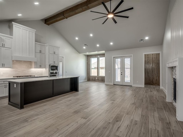 kitchen featuring white cabinetry, stainless steel microwave, a large island, and french doors