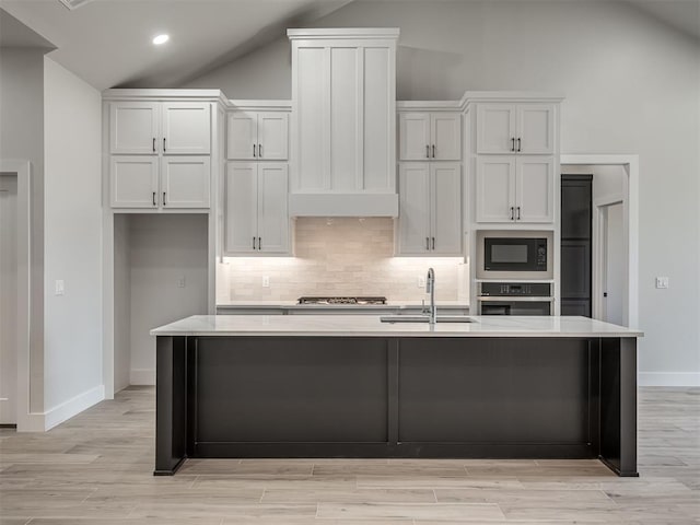 kitchen with sink, stainless steel appliances, white cabinets, and a center island with sink