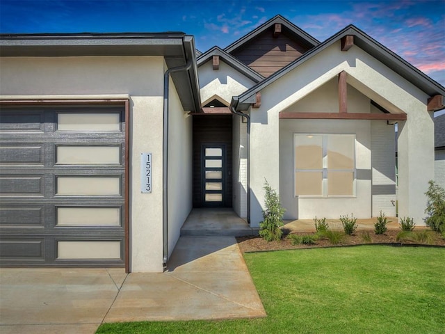 exterior entry at dusk featuring a garage and a lawn