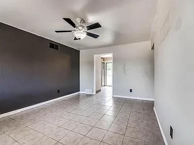 spare room with ceiling fan and light tile patterned floors