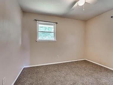 carpeted spare room featuring ceiling fan