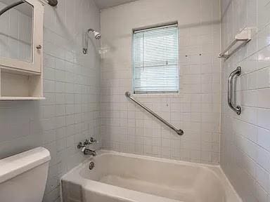 bathroom with tiled shower / bath combo and toilet