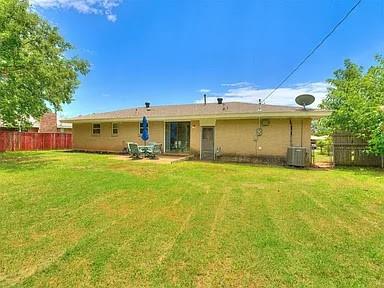 rear view of house with a yard and central air condition unit